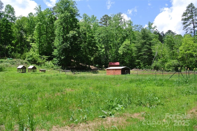 view of yard with a wooded view, a view of countryside, and an outbuilding