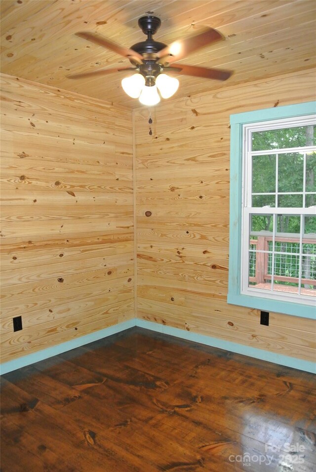 unfurnished room with dark wood-style flooring, a ceiling fan, baseboards, wooden ceiling, and wooden walls