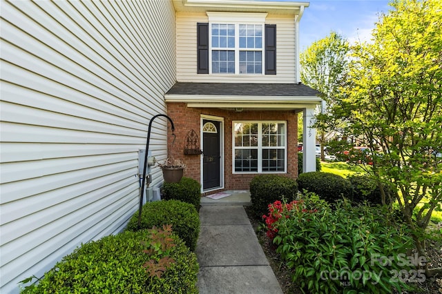 entrance to property with brick siding and roof with shingles