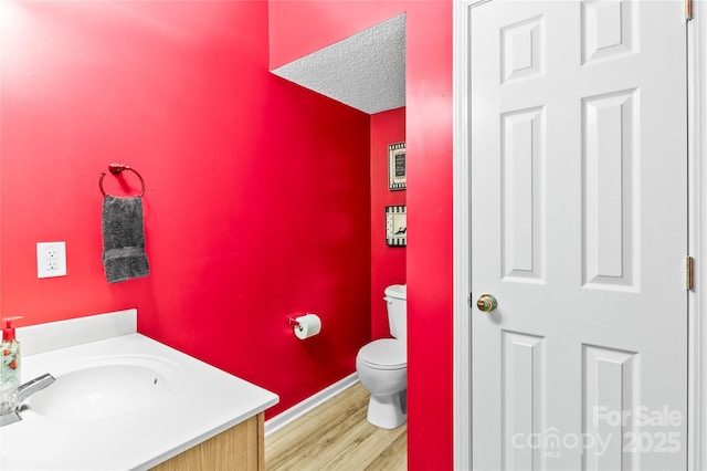 bathroom with wood finished floors, toilet, baseboards, and vanity