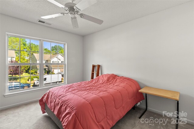 carpeted bedroom featuring baseboards, a textured ceiling, and a ceiling fan