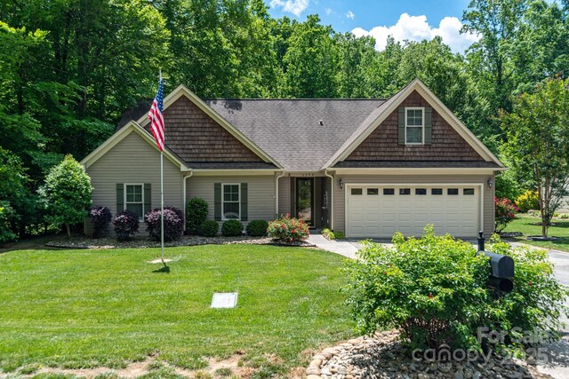 craftsman-style home featuring driveway, a front yard, and an attached garage
