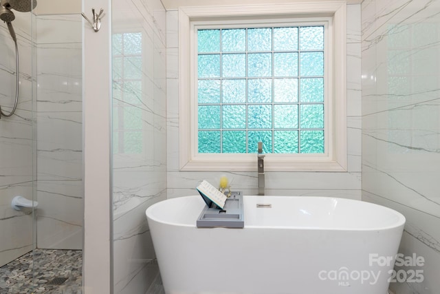 bathroom with tile walls, a marble finish shower, plenty of natural light, and a soaking tub