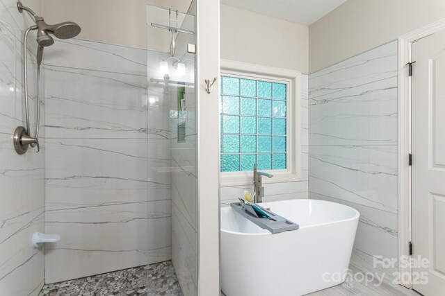 full bathroom with walk in shower, tile walls, and a soaking tub