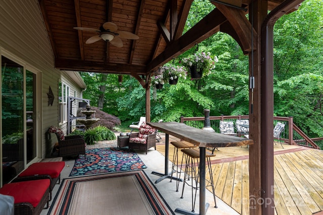 wooden terrace with a ceiling fan and outdoor dining space