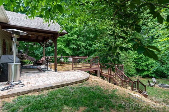 view of green lawn with a fire pit, a deck, stairs, and a patio