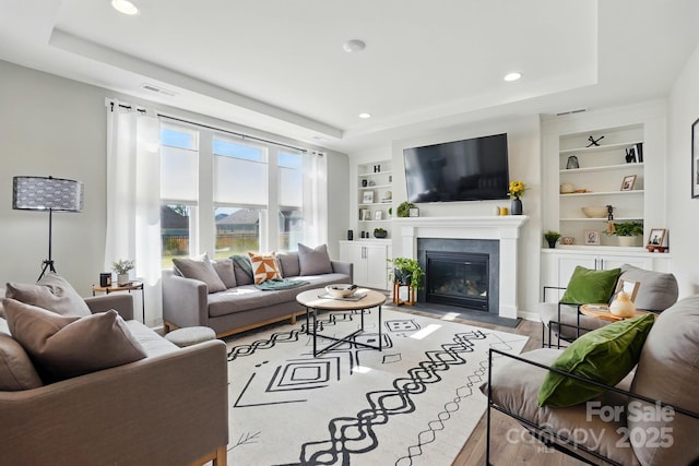 2062 Nellies Way, Fort Mill, SC 29715 - living area with a tray ceiling, built in features, recessed lighting, a fireplace with flush hearth, and wood finished floors