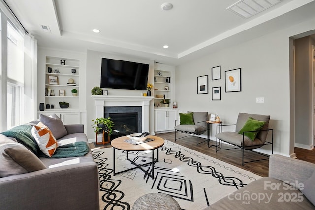 2062 Nellies Way, Fort Mill, SC 29715 - living area featuring built in shelves, wood finished floors, healthy amount of natural light, a raised ceiling, and recessed lighting