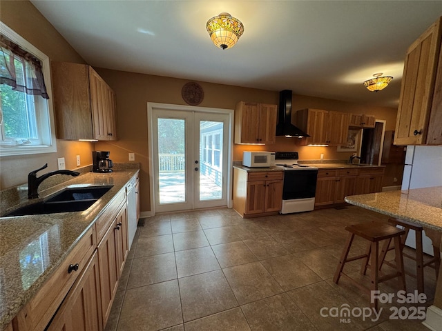 kitchen with white appliances, wall chimney range hood, a sink, and french doors