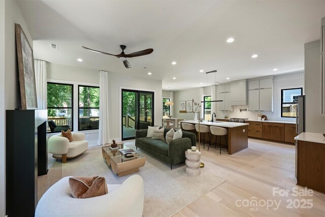 living room featuring healthy amount of natural light, light wood-style flooring, recessed lighting, and ceiling fan