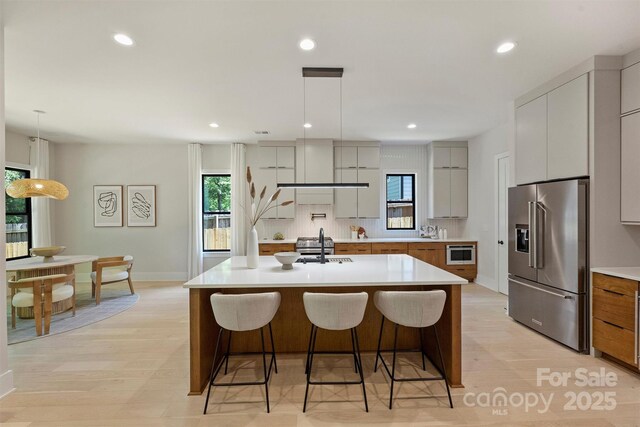 kitchen featuring high quality fridge, light countertops, a kitchen breakfast bar, backsplash, and recessed lighting