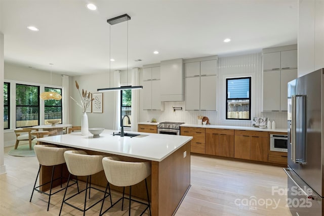 kitchen featuring stainless steel appliances, a sink, modern cabinets, brown cabinets, and decorative backsplash