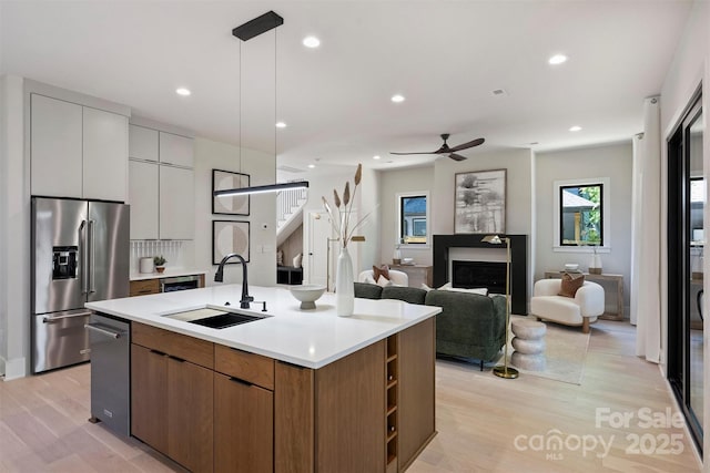 kitchen featuring high end fridge, a sink, modern cabinets, light wood-style floors, and recessed lighting
