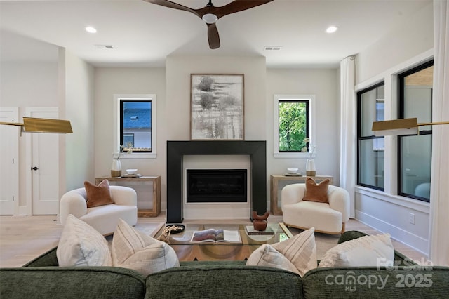living area featuring a ceiling fan, wood finished floors, a fireplace with flush hearth, recessed lighting, and baseboards