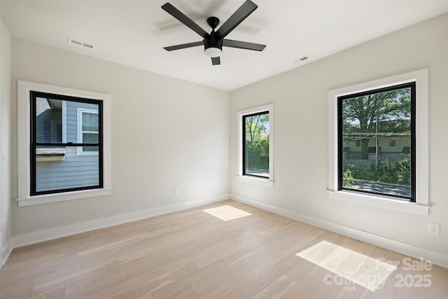 spare room with light wood-type flooring, plenty of natural light, and baseboards
