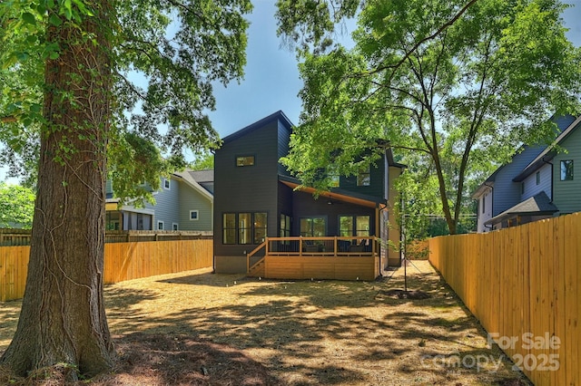 rear view of house featuring a fenced backyard and a wooden deck