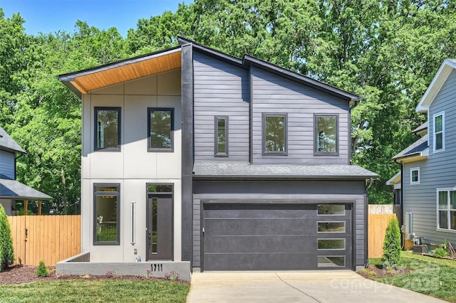 modern home featuring fence, driveway, and an attached garage