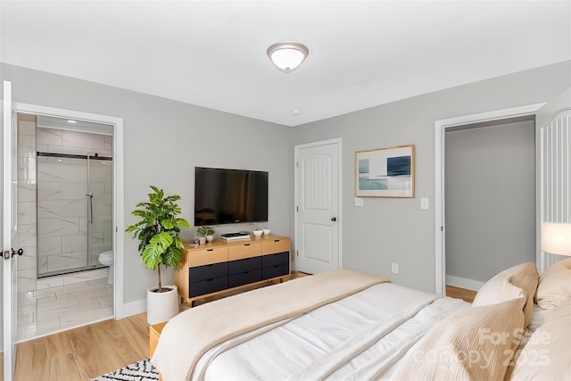 bedroom featuring baseboards, ensuite bathroom, and light wood-style flooring