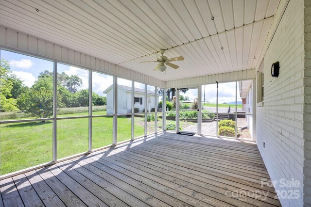 unfurnished sunroom featuring a ceiling fan