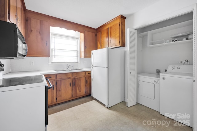 kitchen with freestanding refrigerator, black microwave, electric range oven, a sink, and washer and clothes dryer