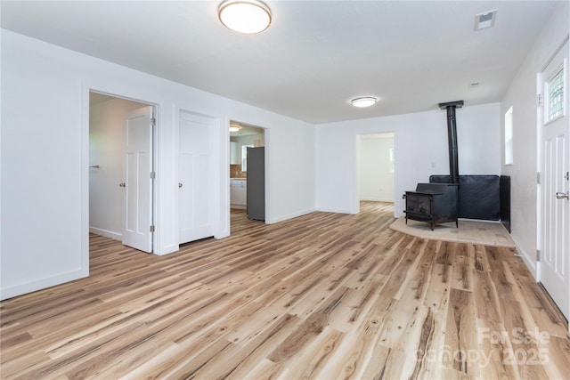 1318 Crawford Rd, Waynesville, NC 28785 - unfurnished living room with a wood stove, light wood-style floors, and baseboards
