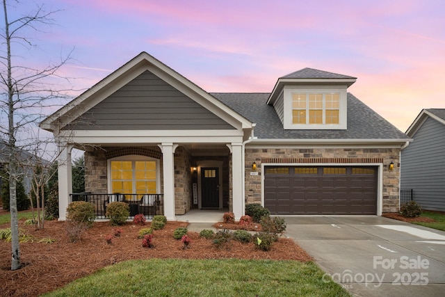view of front of property with stone siding, concrete driveway, a porch, roof with shingles, and an attached garage