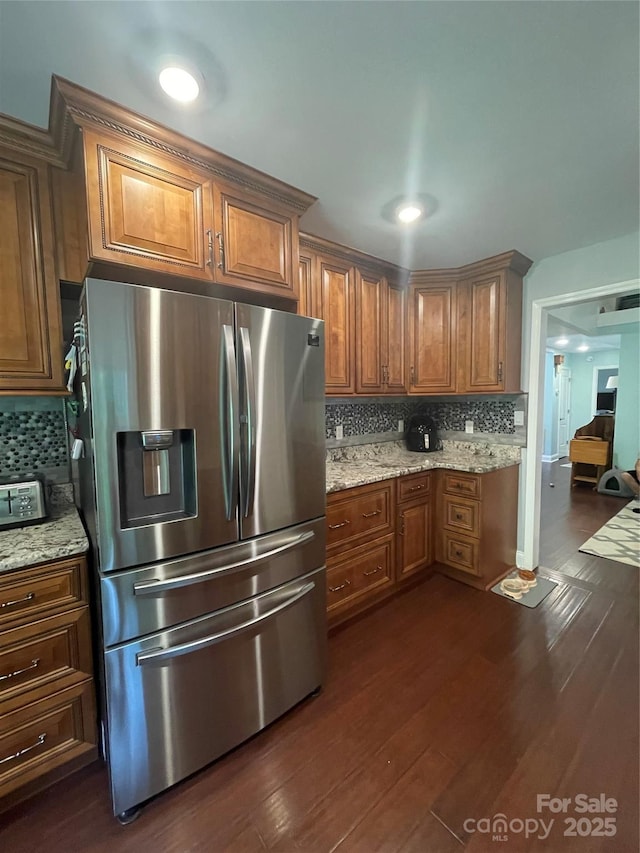 517 Grassy Creek Run, Chester, SC 29706 - kitchen with stainless steel fridge, brown cabinetry, backsplash, dark wood finished floors, and light stone counters