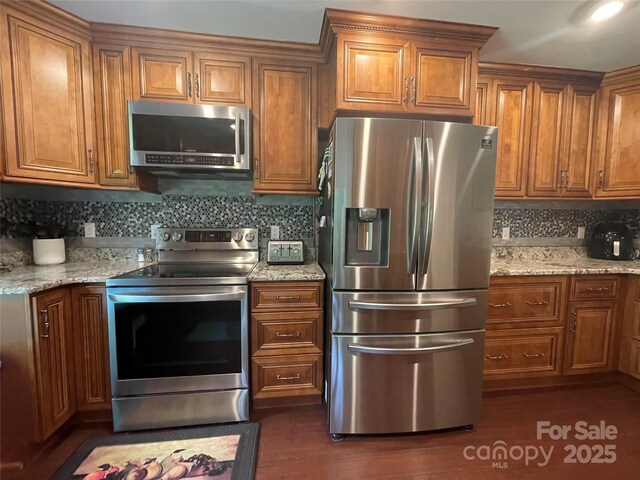 517 Grassy Creek Run, Chester, SC 29706 - kitchen with stainless steel appliances, brown cabinetry, decorative backsplash, and light stone counters