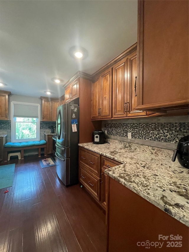 517 Grassy Creek Run, Chester, SC 29706 - kitchen with freestanding refrigerator, decorative backsplash, dark wood finished floors, brown cabinets, and light stone counters