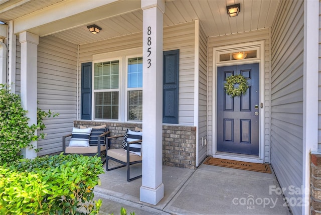 view of exterior entry featuring a porch and stone siding