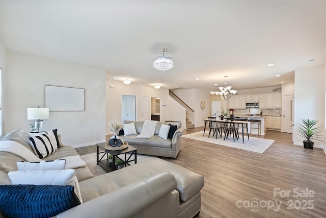 living room with stairs, a chandelier, baseboards, light wood finished floors, and recessed lighting