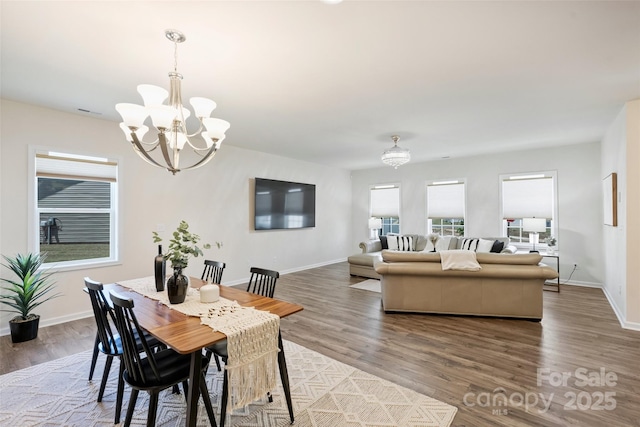 dining space with a chandelier, wood finished floors, and baseboards