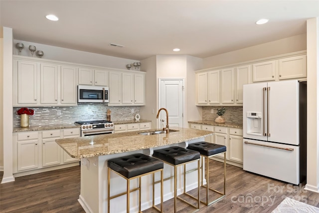 kitchen with white refrigerator with ice dispenser, a sink, gas range oven, backsplash, and white cabinets