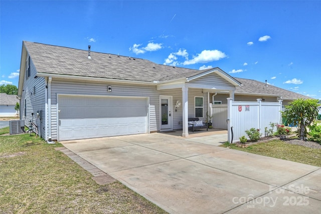 ranch-style home with concrete driveway, a garage, fence, roof with shingles, and central AC unit
