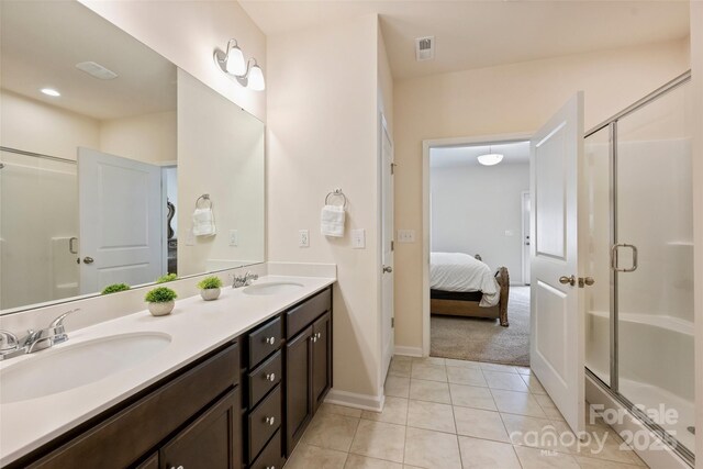 ensuite bathroom with a stall shower, double vanity, baseboards, and tile patterned floors
