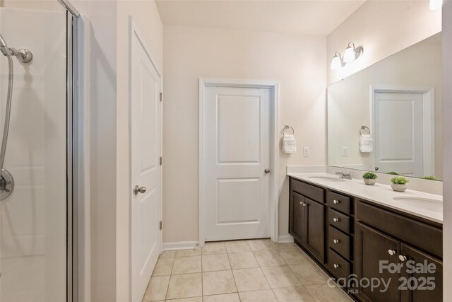 bathroom with tile patterned floors, an enclosed shower, double vanity, and baseboards
