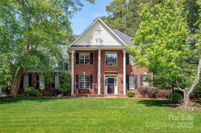 greek revival house featuring a front yard and brick siding