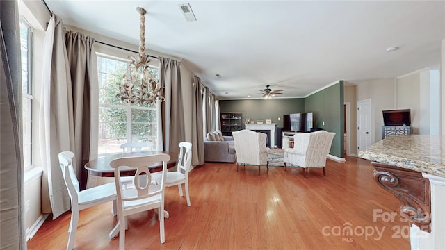 dining space with ceiling fan, light wood-style flooring, and a fireplace