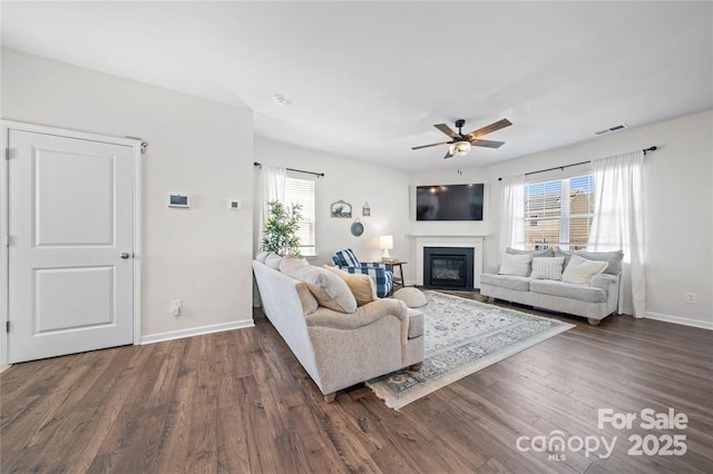 living area with a ceiling fan, plenty of natural light, and dark wood finished floors