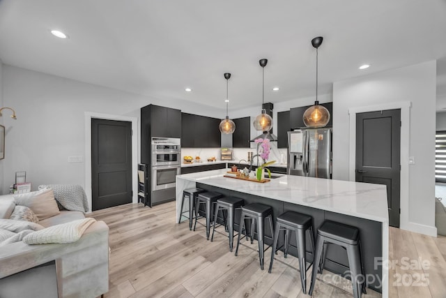 5262 Mckenzie Trl, Conover, NC 28613 - kitchen featuring stainless steel appliances, a kitchen bar, light wood-style flooring, light stone countertops, and recessed lighting