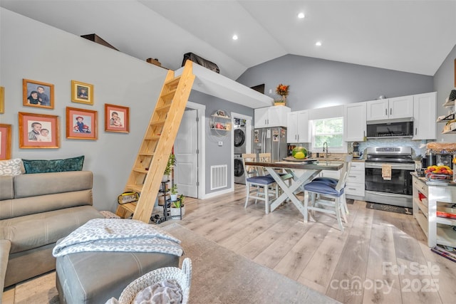 5262 Mckenzie Trl, Conover, NC 28613 - living area featuring stacked washing machine and dryer, high vaulted ceiling, light wood finished floors, and recessed lighting