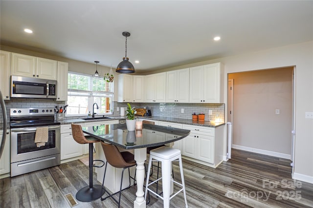 8024 Eagle St, Mount Pleasant, NC 28124 - kitchen with appliances with stainless steel finishes, a sink, a breakfast bar area, decorative backsplash, and dark wood finished floors