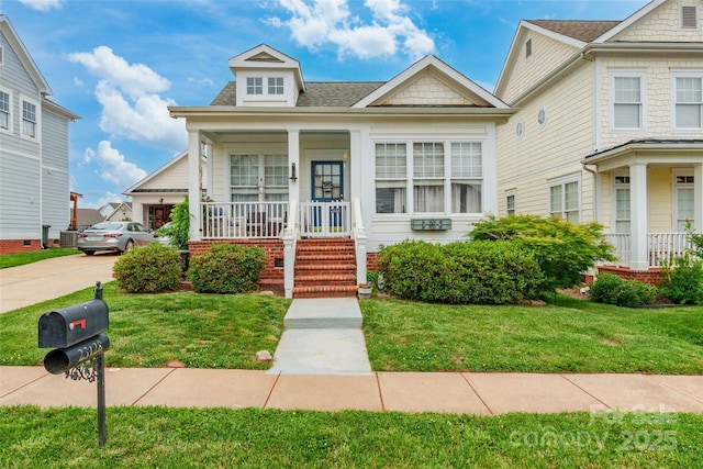 view of front of house featuring covered porch, a front yard, and a shingled roof