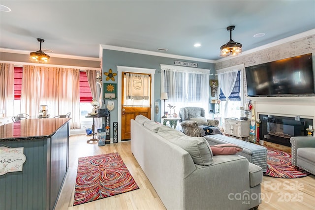 living room with healthy amount of natural light, light wood-style flooring, and ornamental molding
