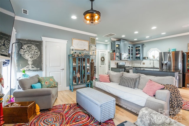 living room featuring ornamental molding, light wood-style floors, and recessed lighting