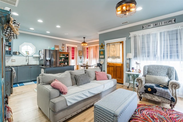 living area featuring light wood-style flooring, ornamental molding, and recessed lighting