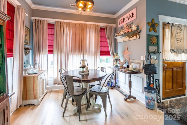 dining space featuring light wood-type flooring and crown molding