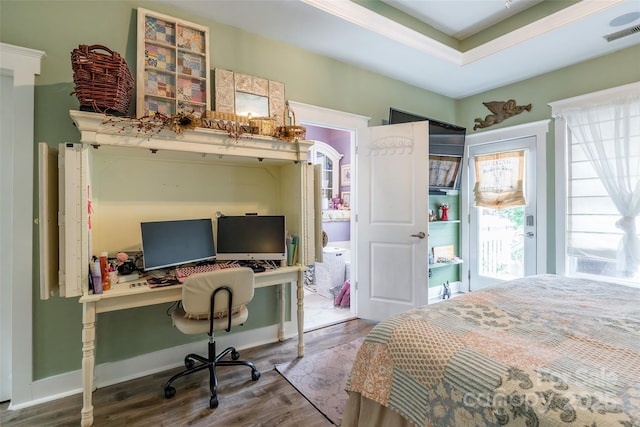 bedroom with wood finished floors and an office area