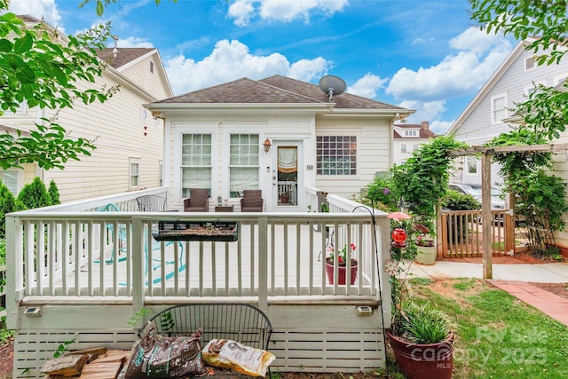 back of property featuring a shingled roof and a deck