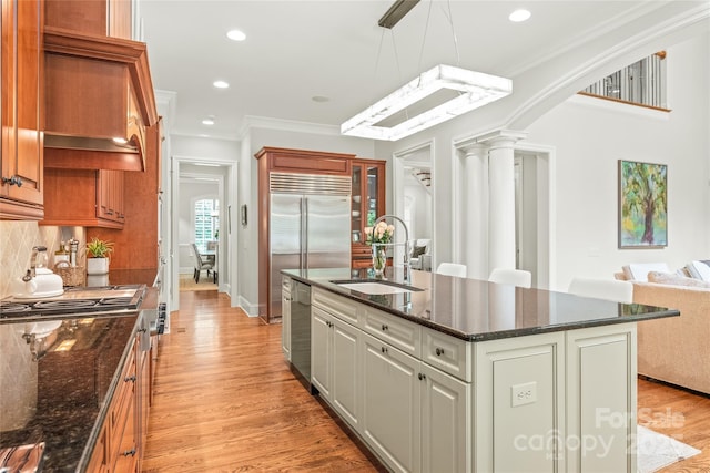 6831 Conservatory Ln, Charlotte, NC 28210 - kitchen featuring a sink, appliances with stainless steel finishes, a center island with sink, light wood-type flooring, and ornate columns